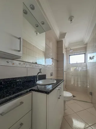 Imagem de um banheiro com revestimento de cerâmica e bancada de granito preto.