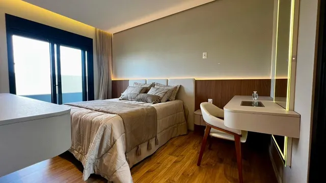 Quarto com cama grande e grandes janelas com vista para o exterior.