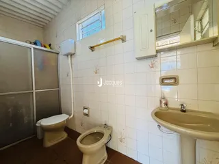 Foto de um banheiro com revestimento de azulejos brancos e piso marrom.