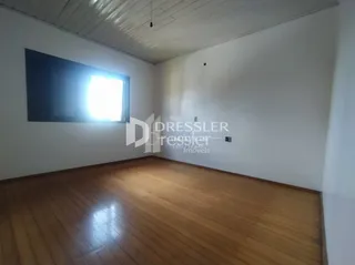 Sala de estar com piso de madeira clara e paredes brancas.