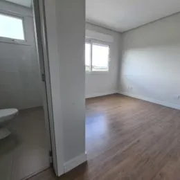 Ambiente interno com piso de madeira clara e paredes brancas.