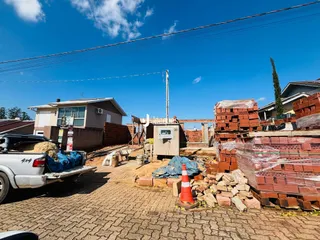 Vista externa de uma propriedade em construção com materiais de tijolo e caminhão.