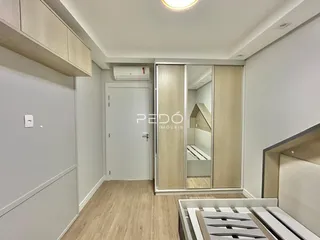 Vista de um corredor interno com portas brancas e piso de madeira clara.