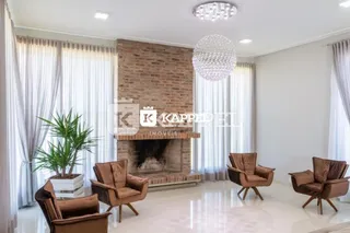 Sala de estar com lareira de tijolos e cortinas brancas.