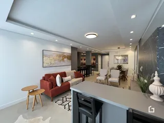 Sala de estar moderna com sofá e área de jantar em um apartamento.