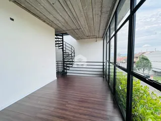 Vista interna de um corredor com piso de madeira e grande janela.