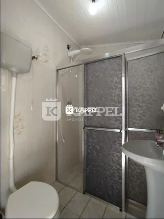 Foto interna de um banheiro com box de vidro e vaso sanitário.