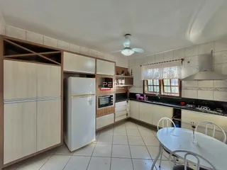 A cozinha apresenta armários brancos e bancadas escuras com piso de cerâmica.