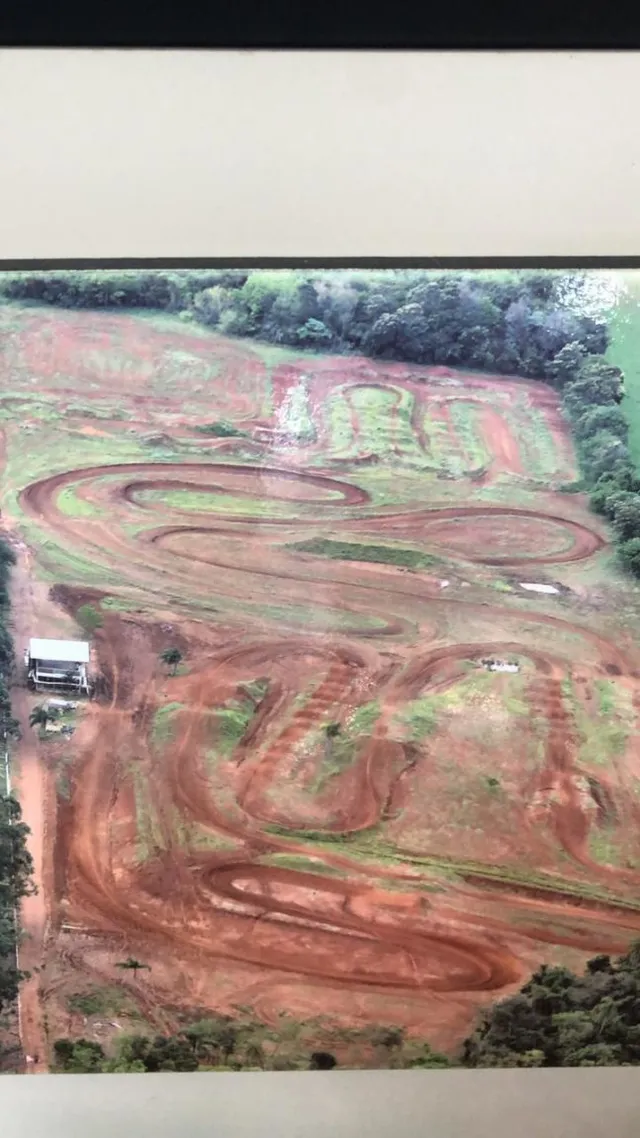 Vista aérea de uma área de terra com sulcos e vegetação ao redor.