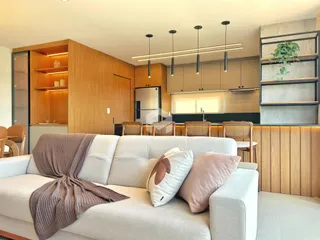Sala de estar moderna com cozinha integrada e painéis de madeira.