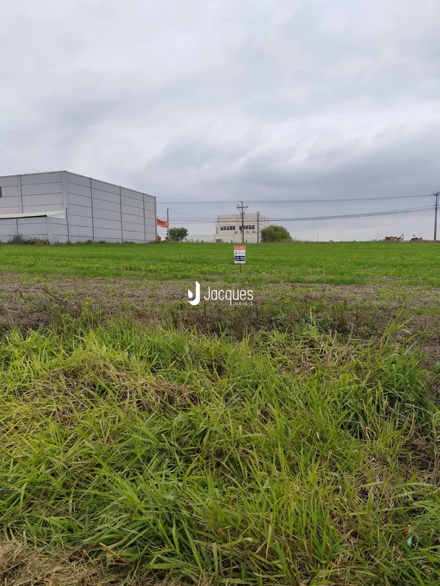Foto da fachada de uma propriedade em Lajeado, Brasil, mostrando um campo gramado e um prédio ao fundo.