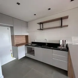 Cozinha moderna com armários brancos e bancada escura.