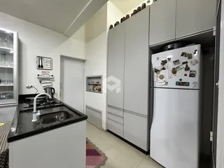 Vista da cozinha moderna com armários brancos e bancada escura.