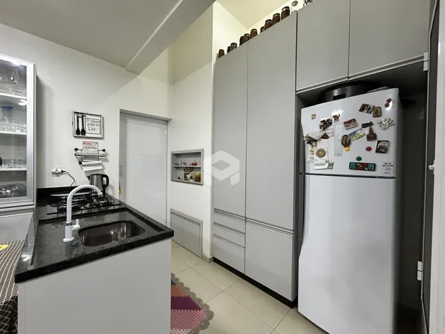Vista da cozinha moderna com armários brancos e bancada escura.