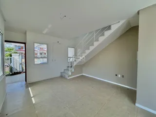 Ambiente interno de uma sala ampla com piso de cerâmica e escadaria.