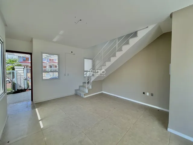 Ambiente interno de uma sala ampla com piso de cerâmica e escadaria.