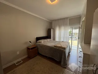 Quarto com cama e piso de madeira no interior da residência.