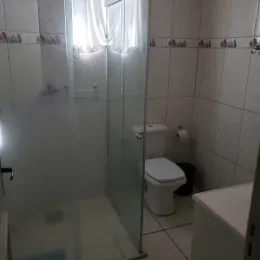 Banheiro com box de vidro e revestimento de azulejos brancos.