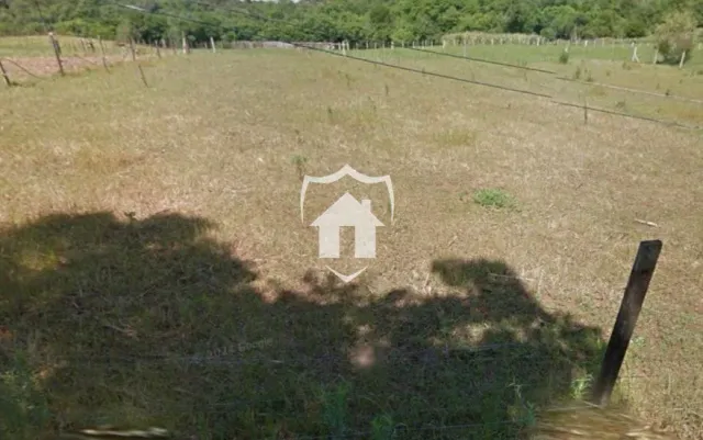 Campo aberto com grama e sombra em uma propriedade.