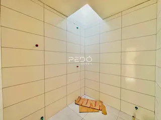 Corredor interno com paredes brancas e piso claro em uma residência.