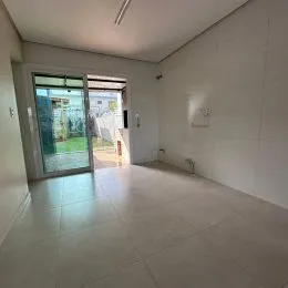Hall de entrada com piso claro e porta de vidro.