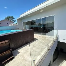 Vista externa de uma piscina com deck de vidro em uma residência.