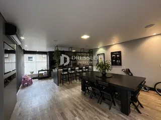 A sala de estar apresenta piso de madeira clara e uma mesa escura.