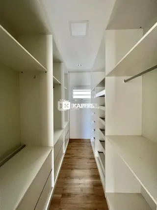 Corredor longo com armários embutidos e piso de madeira clara.