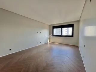 Uma sala de estar ampla com piso de madeira clara.