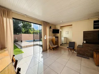 Sala de estar com porta de vidro abrindo para um pátio com piscina.