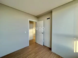 Hall de entrada com piso de madeira clara e porta branca.