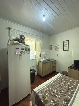 Ambiente interno de uma sala com piso de madeira e cortinas claras.