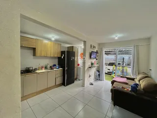 Vista de uma sala de estar com cozinha aberta e acesso ao jardim.