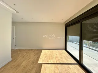 Sala de estar com piso de madeira e porta de vidro que dá para o exterior.
