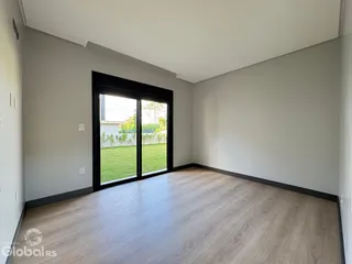 Sala de estar com piso de madeira e grande janela de vidro.