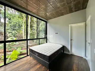 Quarto com grande janela de vidro e piso de madeira.