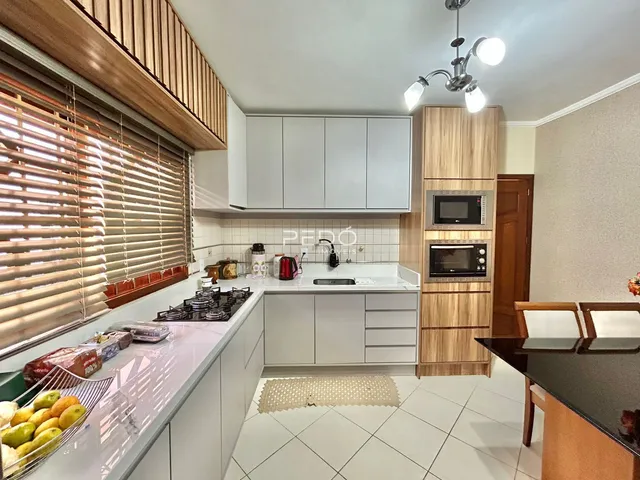 Cozinha moderna com armários brancos e bancadas claras.