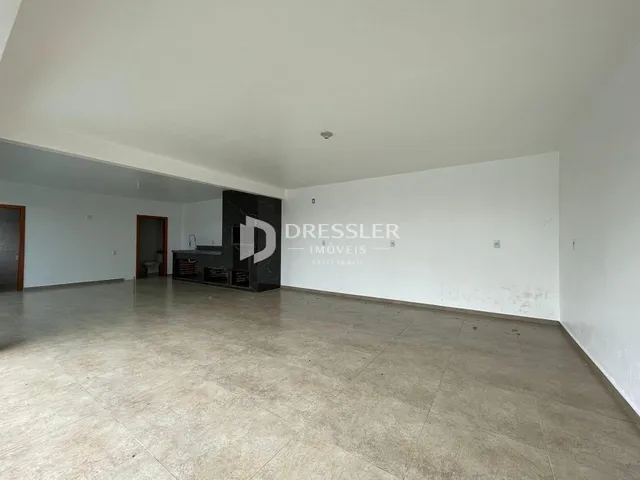 Ambiente interno vazio com piso de concreto e paredes brancas.