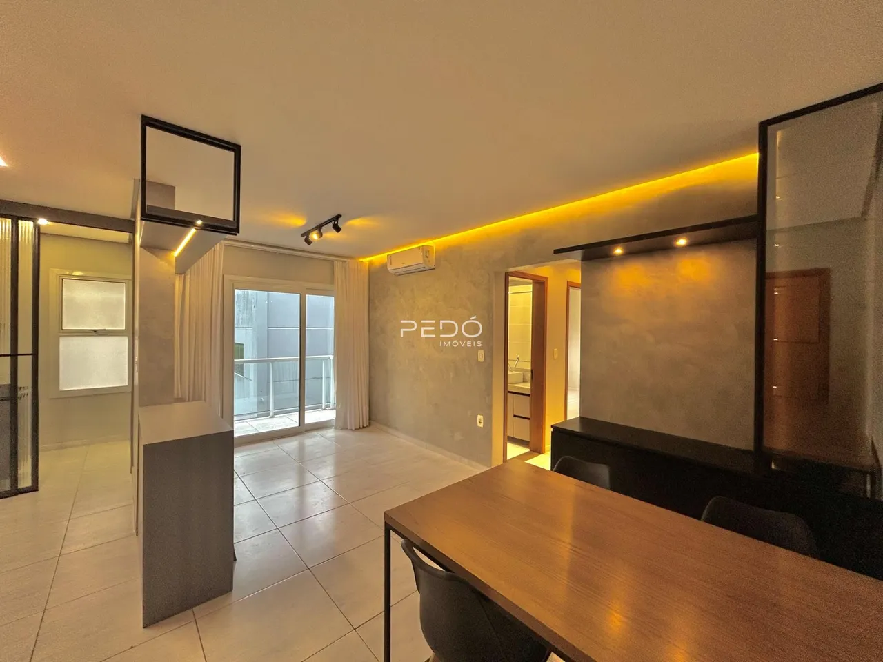 Ambiente interno de uma sala com piso de cerâmica e grandes portas de vidro.
