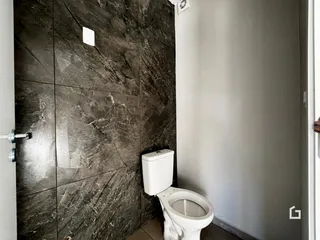 Parede com revestimento de mármore escuro e vaso sanitário branco em um ambiente interno.