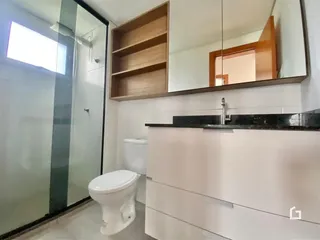 Foto de um banheiro com box de vidro e vaso sanitário.