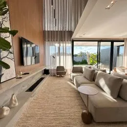 Uma sala de estar moderna com sofá claro e cortinas transparentes.