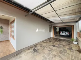 Vista de uma área externa coberta com piso de pedra e estrutura de telhado metálico.