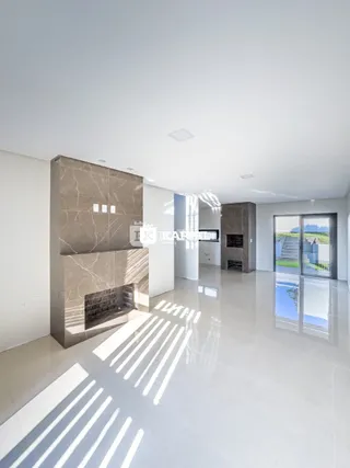 Sala ampla com lareira e piso claro em ambiente moderno.