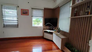 Sala de estar com piso de madeira e televisão na parede.
