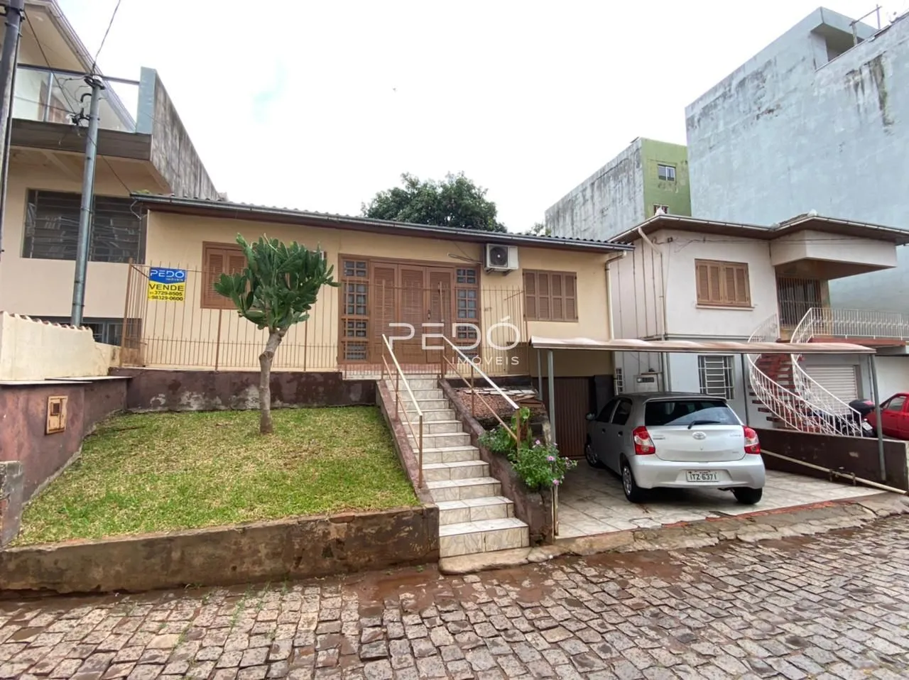 Fachada de uma residência em Lajeado, Brasil, com jardim e acesso por escadas.