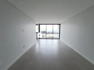 Hall de corredor longo com paredes brancas e grande janela.