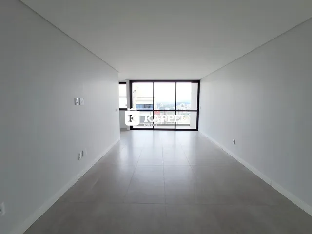 Hall de corredor longo com paredes brancas e grande janela.