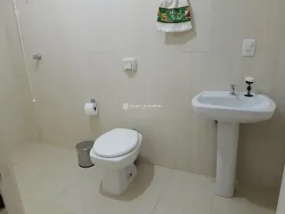 Foto de um banheiro mostrando um vaso sanitário e uma pia brancas.