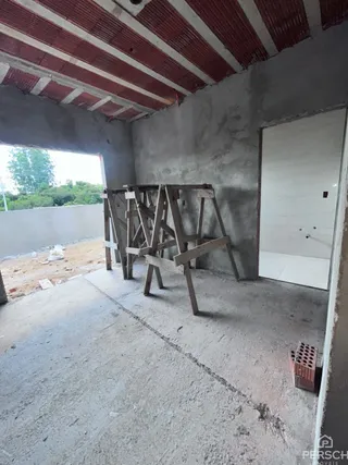 Foto de um espaço interno em construção com estrutura de madeira aparente e paredes de concreto.